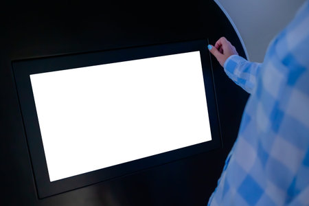 Woman looking at blank digital interactive white display kiosk at exhibition or museum with futuristic sci-fi interior. Mock up, copyspace, template, white screen, technology conceptの写真素材