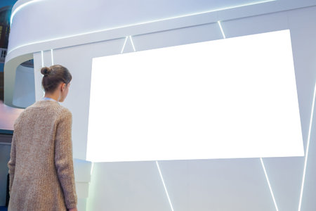 White screen, mock up, future, copyspace, template, isolated, technology concept. Woman looking at blank digital interactive white display wall at exhibition or museum with futuristic scifi interiorの写真素材