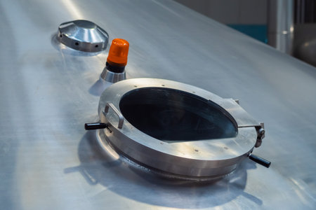 Pressure glass manhole on steel tank for wort boiling at beer factory. Brewery equipment,...