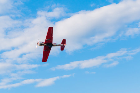 Small retro airplane, light aircraft flying in blue cloudy sky and doing stunts at Air Show. Performance, extreme, aerobatic and sport conceptの写真素材