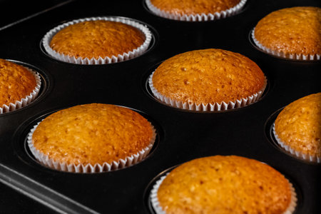 Baked cupcakes, muffins in muffin tin in electric oven - close up view. Homemade bakery, food,...