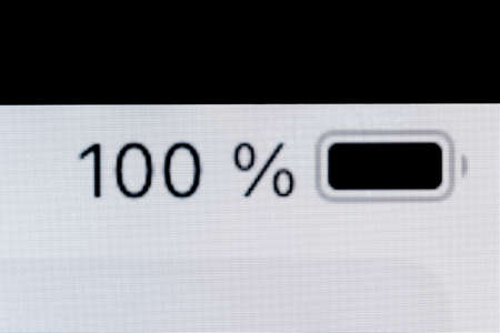 Smartphone full charged pixel battery level indicator - one hundred, 100 percent: close up macro view of gadget display, screen. Energy, technology, power, digital and symbol conceptの写真素材