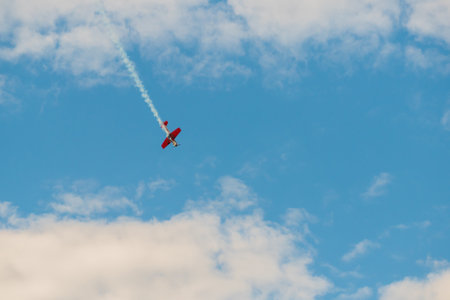 Small retro airplane, light aircraft flying in blue cloudy sky and doing stunts at Air Show. Performance, extreme, aerobatic and sport conceptの写真素材