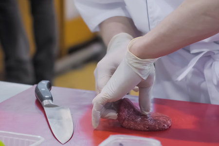 Chef hands holding knife and preparing minced meat burger cutlet on red cutting board - close up....