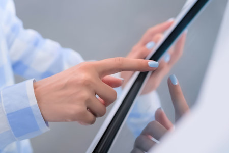 Woman hand using interactive touchscreen display of white electronic multimedia kiosk at technology...