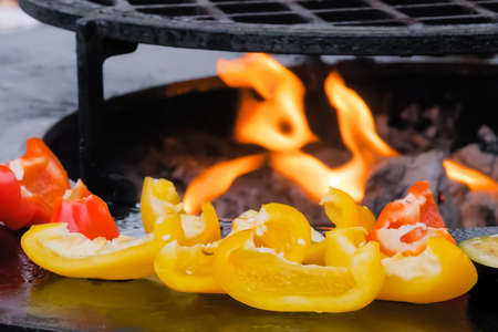Process of cooking vegetable - bell peppers on grill at summer outdoor food market - close up. Professional cooking, catering, cookery, barbecue, gastronomy and street food conceptの写真素材