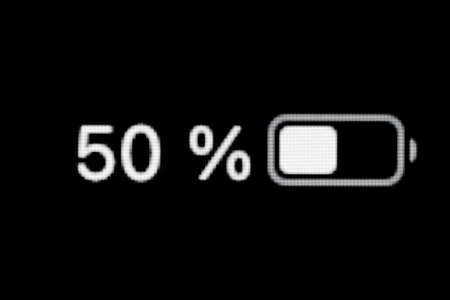 Smartphone charged battery level indicator - fifty, 50 percent: close up macro view of gadget display, screen. Energy, technology, power, digital and symbol conceptの写真素材