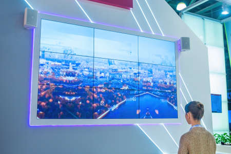 MOSCOW, RUSSIA - JUNE 05, 2019: Technology exhibition. Woman looking at large wide interactive wall display at museum with futuristic sci-fi interior. Education, futuristic conceptのeditorial素材