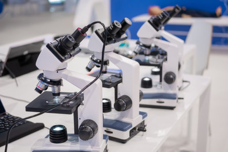 Microscopes on white table at medical technology exhibition, trade show. Laboratory equipment, science, medical, optical, pharmaceutical and education conceptの写真素材