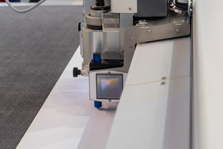 Flatbed cutter, router with drawing pen module writing text on white plastic sheet. Technology,...