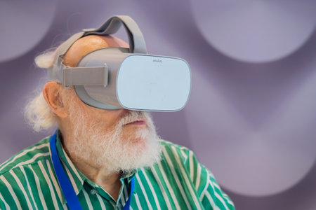 MOSCOW, RUSSIA - JANUARY 5, 2020: Interactive VR exhibition. Elderly man with beard using virtual reality headset and looking around - close up. Technology, augmented reality and entertainment conceptのeditorial素材