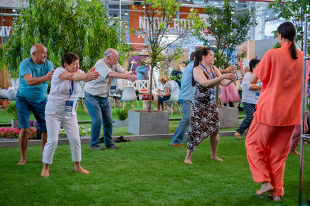 MOSCOW, RUSSIA - JANUARY 5, 2020: Sport exhibition. Group of old people doing stretching, balancing yoga exercise at fitness event. Wellness, praticing, training, active old age conceptのeditorial素材