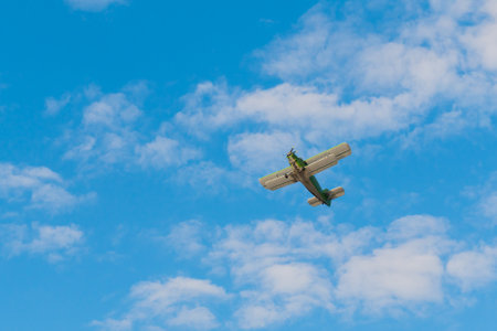 Green biplane, retro airplane flying in blue sky and doing stunts at Air Show. Performance, extreme, aerobatic, sport and aircraft conceptの写真素材