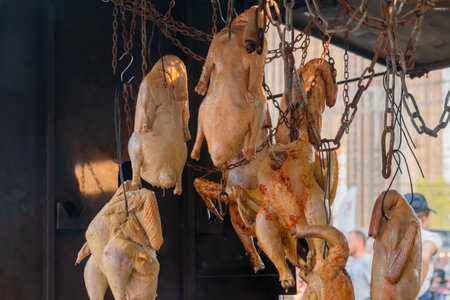 Hanging whole chickens smoking over fire or coals at summer local food market. Outdoor cooking, barbecue, gastronomy, cookery and street food conceptの写真素材