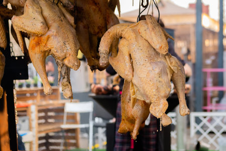 Hanging whole chickens smoking over fire or coals at summer local food market - close up, selective...