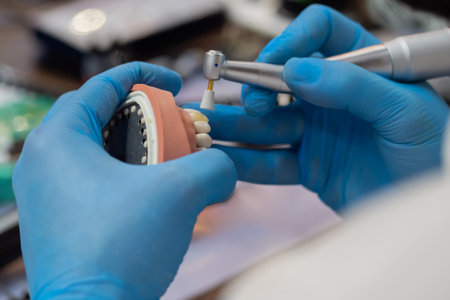 Close up view: professional dental technician or dentist hands holding motor handpiece tool and...
