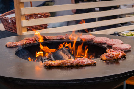 Process of grilling fresh juicy meat steaks and cutlets for burgers on brazier with hot flame at...