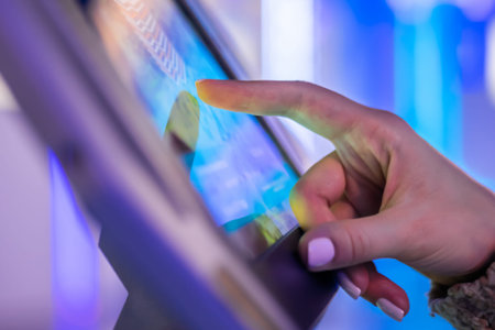 Woman hand using touchscreen display of interactive floor standing tablet kiosk at exhibition or...