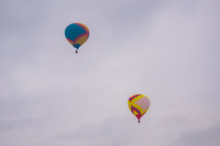Two colorful hot air balloons flying against grey sky at Winter aerostat festival. Freedom, sport, aircraft conceptの写真素材
