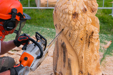 NIZHNY NOVGOROD, RUSSIA - JUNE 15, 2020: Summer Outdoor Festival. Man carpenter, wood sculptor using chainsaw for carving wooden sculpture. Carpentry, craftsmanship, design conceptのeditorial素材