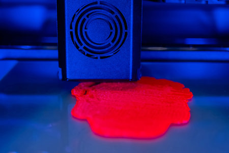 Print head of three dimensional printer machine printing red flat plastic model at modern...