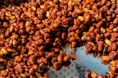 Heap of roasted caramelized sugared peanuts with warm and contrast sunlight illumination at summer outdoor food market - close up. Cookery, dessert, gastronomy and street food conceptの写真素材