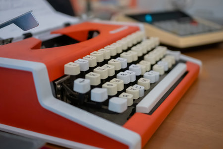 Old vintage orange typewriter with a sheet of paper on table at museum, exhibition - close up, selective focus. Retro, nostalgia and communication conceptの写真素材