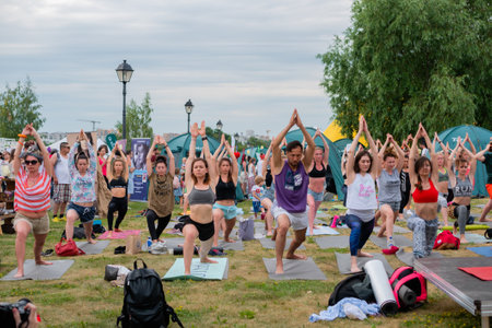 MOSCOW, RUSSIA - MAY 5, 2019: Summer yoga festival. Group of people doing stretching and yoga exercises at forest, park - front view. Fitness, sport, outdoor activity and relaxation conceptのeditorial素材