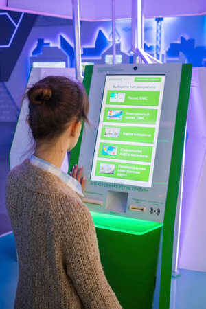 MOSCOW, RUSSIA - JUNE 05, 2019: Technology exhibition. Woman using interactive touchscreen display of electronic document informational kiosk at museum. Education, futuristic, technology conceptのeditorial素材
