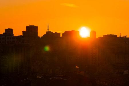 Amazing orange sunset sky with the setting sun over the city of Istanbul, Turkey in the evening - apartment, residential buildings silhouettes. Urban, cityscape, oriental and summer concept