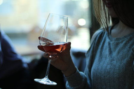 Beautiful woman holding a wine glass. There's rosÃ© wine in the glass. The woman's face is not...