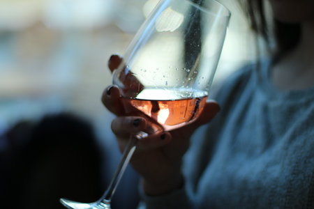 The woman has a wine glass in her hand. There is pink wine in the glass.の写真素材