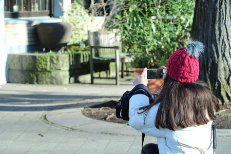 Tourist girl takes photos of surroundings with her mobile phone. The girl is wearing a red beret.の写真素材