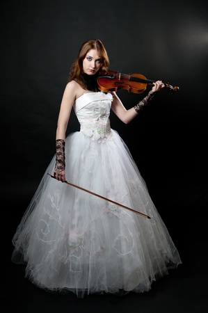 Girl in white dress with violin on black backgroundの写真素材