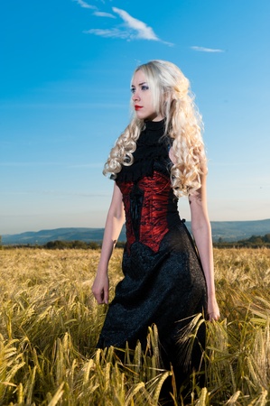 portrait of beautiful girl blonde gothic in wheat fieldの写真素材