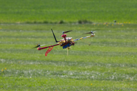 The quadrocopter flying over the green field