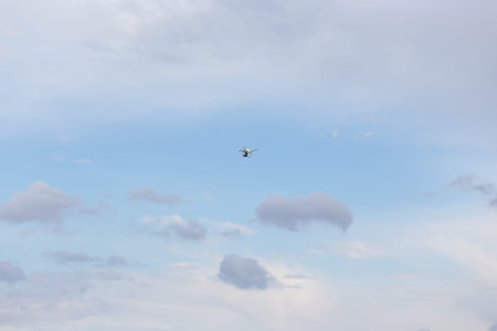 Small drone is flying high above the green field