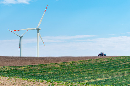 The windmills and the tractor working on the large fieldの写真素材