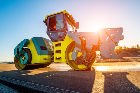 Beautiful sunset above the road roller working on the new road construction siteの写真素材