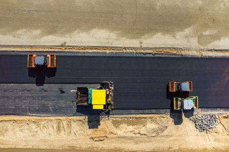 Aerial view on the road rollers working on the new road construction site