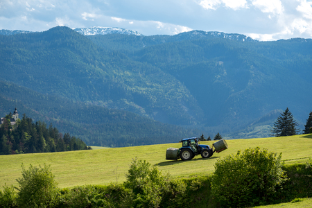 Large view on the tractor collecting the grass from the meadowの写真素材