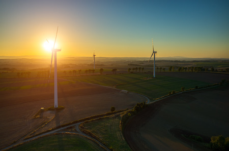 Beautiful sunset above the windmills on the fieldの写真素材