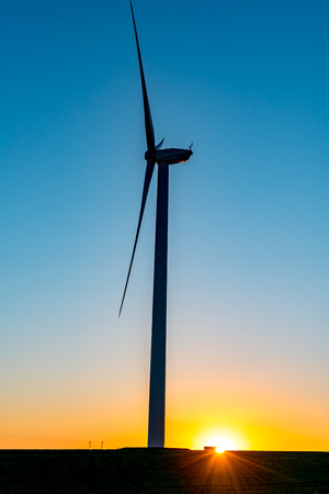 Beautiful sunset above the windmill on the fieldの写真素材