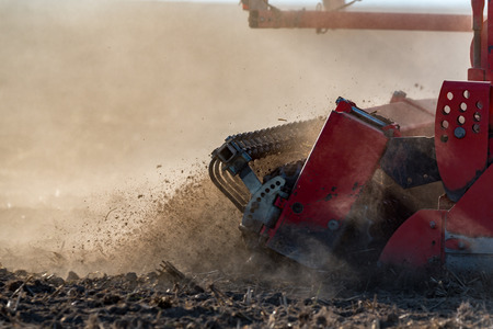 The tractor working on the brown fieldの写真素材