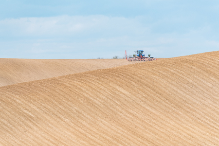 Large view on the tractor harrowing the field in spring seasonの写真素材