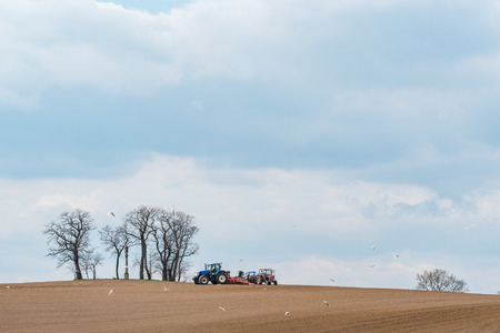 Large view on the tractor harrowing the field in spring seasonの写真素材