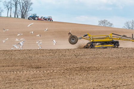Close view on the tractor harrowing the field in spring season