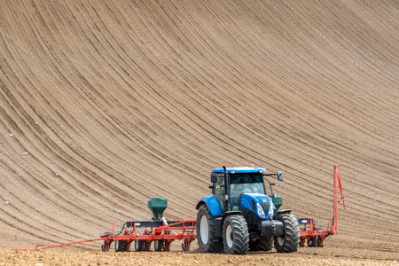 Large view on the tractor harrowing the field in spring seasonの写真素材