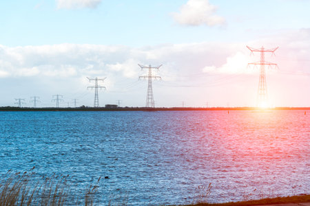 Beatiful sunset above the modern high powerlines in the ocean