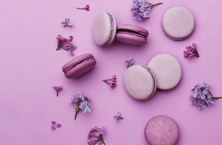 Mix of violet and lilac macarons with lilac flowers on violet background. Top view, flat lay. Abstract food backgroundの写真素材